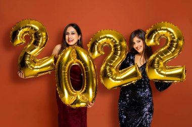 Yeni yıl partisinde elinde 2022 altın balon tutan genç kadınlar