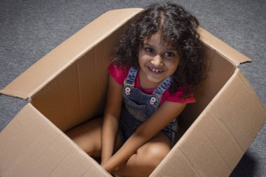 Oyun sırasında kutunun içinde oturan tatlı kız.