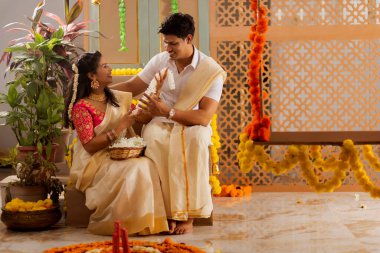 Güney Hintli çift Onam 'ı kutlamak için çiçek çelengi ile evi dekore ediyorlar.