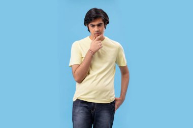 Mavi arka planı olan düşünceli bir gencin portresi.