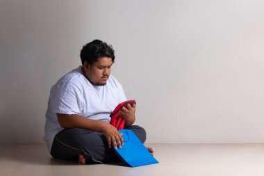 Şişman bir adam dikkatle elindeki kumaşın ebatlarına bakıyor..