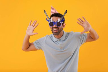 Funny young man wearing guitar shaped eye glasses with party hat clipart