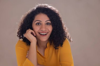 Heyecanlı genç bir kadın kameraya şaşkınlıkla bakıyor.