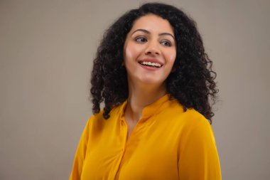 Gri bir geçmişi olan gülümseyen genç bir kadının portresi.