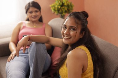 Oturma odasındaki kanepede dinlenen iki genç kadın.