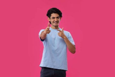 Mavi arka planda dikilirken kamerayı gösteren bir gencin portresi