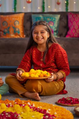Kız, Diwali münasebetiyle yeri çiçeklerle süslüyor.