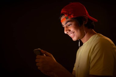 Kırmızı şapkalı genç gece akıllı telefondan film izliyor.