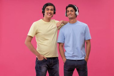 Pembe arka planda müzik dinleyen iki mutlu arkadaş.