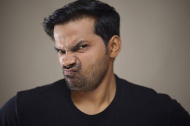 Kameraya öfkeyle bakan genç bir adamın portresi.