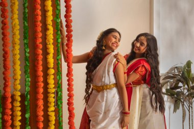 Durga Puja vesilesiyle evde dikilen geleneksel kıyafetli iki Bengalli kız kardeşin portresi.