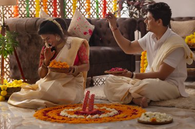 Onam 'da evi dekore ederken karısına gül yaprakları fırlatan bir koca.