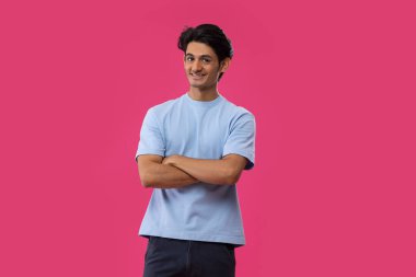 Pembe arka planda duran neşeli bir gencin portresi