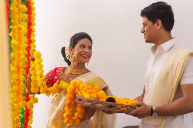 Güney Hintli çift Onam 'ı kutlamak için çiçek çelengi ile evi dekore ediyorlar.