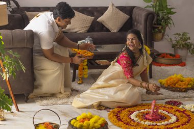 Güney Hintli çift Onam 'ı kutlamak için çiçek çelengi ile evi dekore ediyorlar.