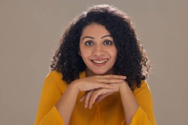 güzel bir genç kadın gülümseyerek kameraya bakıyor