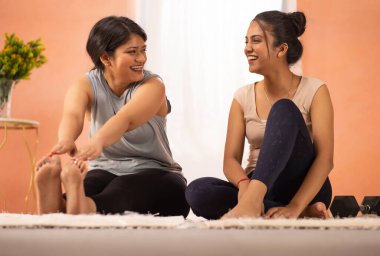 Two young women exercising in living room clipart