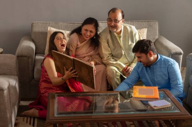 Mutlu Hintli aile evde fotoğraf albümü izliyor.