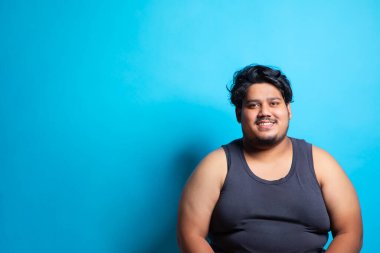 Arkaplanda oturan ve gülümseyen şişman bir adamın portresi..