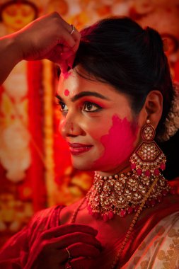 Bengali married woman applying vermillion to each other during celebration of Durga Puja clipart