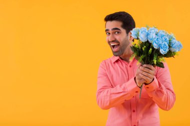 Elinde çiçek buketi tutan mutlu bir gencin portresi.