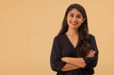 Kollarını kavuşturup kameraya bakan genç bir kadının portresi.