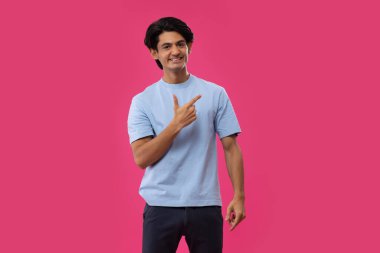 Pembe arka planda el hareketi yapan bir gencin portresi.