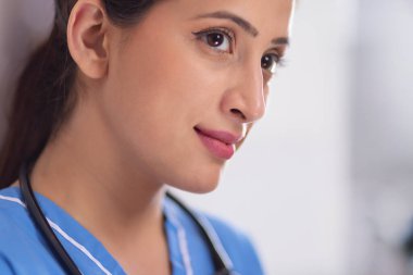 Close-up of a cheerful young female nurse in blue scrub clipart