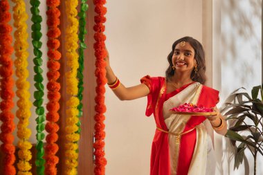 Durga Puja vesilesiyle elinde gül yapraklarıyla duran beyaz sarili Bengalli kız.