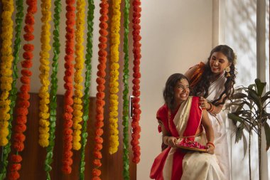 Bengalli iki kız kardeşin portresi Durga Puja vesilesiyle dekorasyon sırasında eğleniyor.