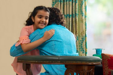 Babasına sarılan güzel bir kız evde kömürde oturuyor.