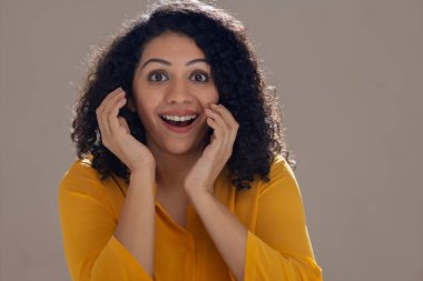 Şaşkınlıkla yüzünü tutan heyecanlı genç bir kadın.