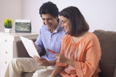 Hintli orta yaşlı çift kredi kartı kullanarak online alışveriş yapıyor.