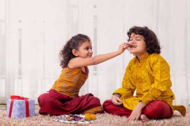 Girl giving her brother bite of chocolate on Bhai Dooj clipart