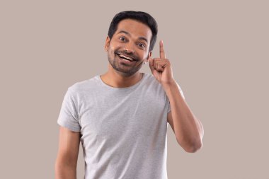 Parmağıyla yukarıyı gösteren mutlu bir gencin portresi.