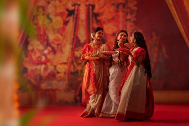 Durga Puja kutlamaları sırasında anneleri ve kızları puja thali ile birlikte duruyorlar.