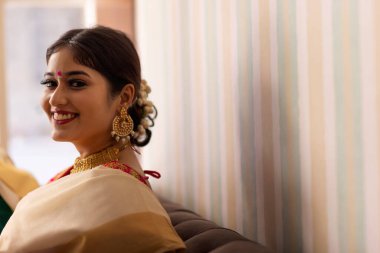 Kanepede otururken kameraya bakan geleneksel neşeli kadın.