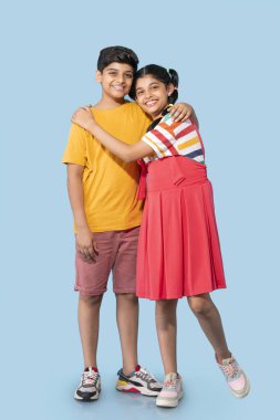 Mavi arka plana sarılan erkek ve kız kardeşlerin portresi