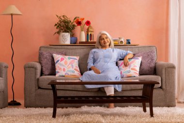 Evdeki kanepede dinlenen yaşlı kadının portresi.