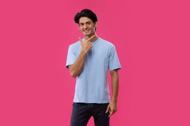 Genç bir çocuk pembe arka planda gülümseme hareketi yapıyor.