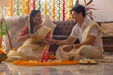 Güney Hintli çift Onam 'ı kutlamak için çiçek çelengi ile evi dekore ediyorlar.