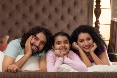 Mutlu aile üyeleri yatakta yatarken birlikte poz veriyorlar.