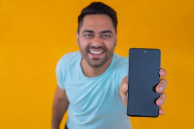 Siyah ekranlı cep telefonu gösteren mutlu genç adam.