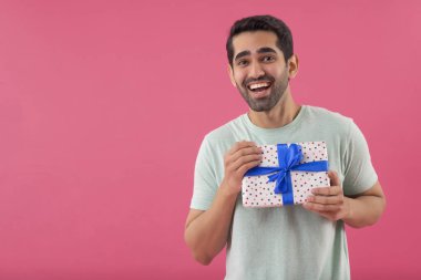Elinde hediyeyle kameraya bakan mutlu genç adamın portresi.