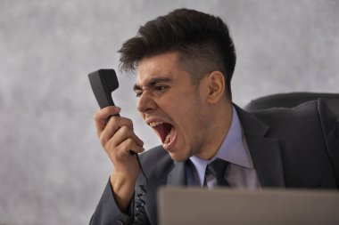 Telefonda bağıran kızgın bir iş adamının yakın plan portresi.