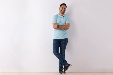 Elleri beyaz arka planda katlanmış genç bir adamın portresi.