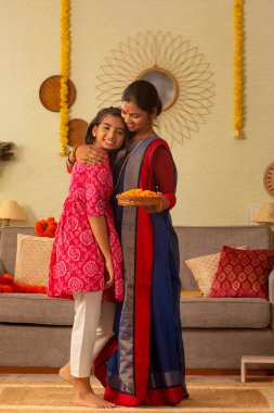 Bengalli bir annenin kızını okşayan portresi.