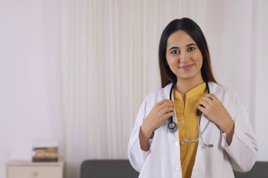 Stetoskop tutan gülümseyen bir bayanın yakın çekimi.