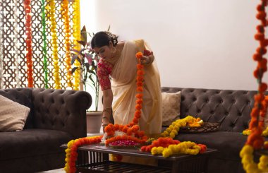 Onam 'ı kutlamak için çiçek çelengi takan beyaz sari elbiseli kadın.