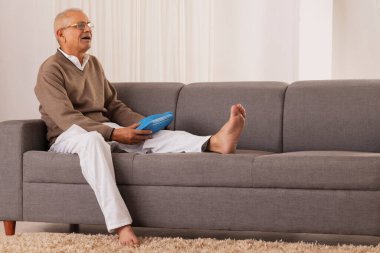 Yaşlı adam diz eklem ağrısından kurtulmak için sıcak su torbası uyguluyor.